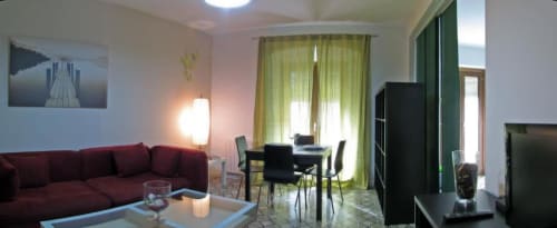 Amplia sala de estar en apartamento de Cáceres con sofá borgoña, cortinas verdes, mesa de comedor y escritorio de trabajo
