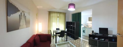 Sala de estar moderna en Cáceres con sofá rojo, escritorio, cocina integrada y detalles en verde