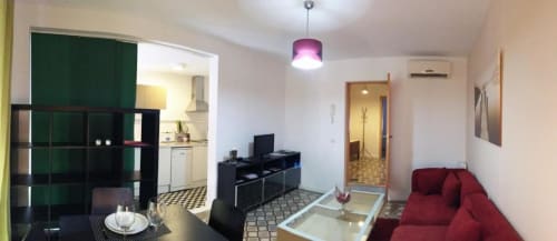 Apartamento moderno en La Machacona, Cáceres, con sofá rojo, cocina y vistas a monumentos