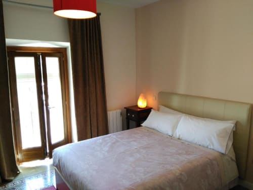 Dormitorio luminoso en Apartamentos La Machacona de Cáceres con cama queen, puertas al balcón y comodidades modernas