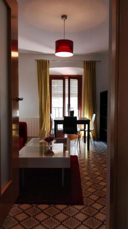 Pasillo moderno de apartamento con lámpara colgante roja, cortinas doradas y zona de comedor en Apartamentos La Machacona, Cáceres