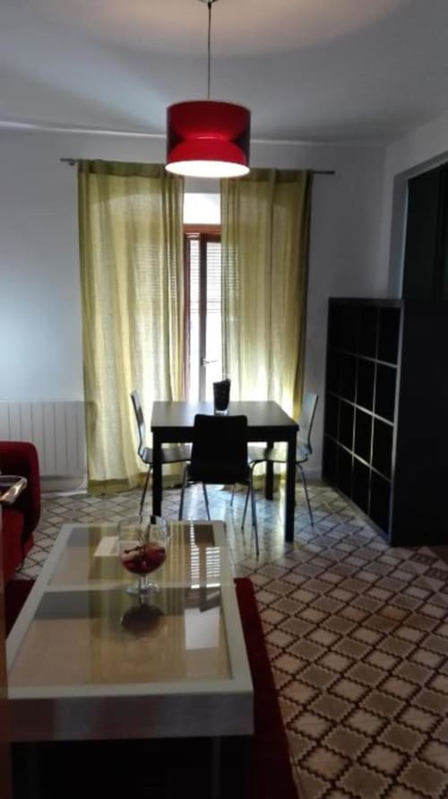 Interior moderno del apartamento en La Machacona, Cáceres con mesa de comedor, lámpara colgante roja y cortinas color oliva con vistas