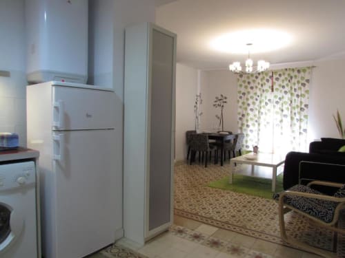 Cocina abierta y sala de estar del apartamento de 1 dormitorio Plaza de Santiago, Cáceres, con electrodomésticos blancos y verde