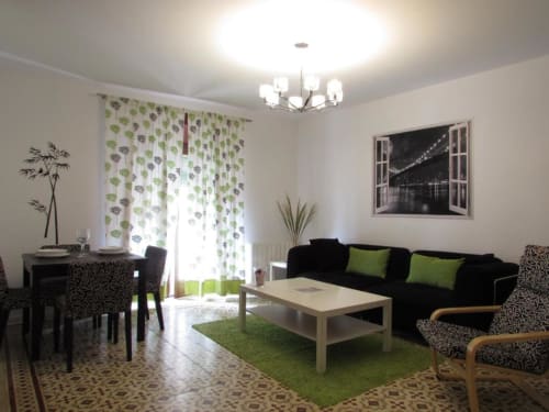 Apartamento moderno de 1 dormitorio en Cáceres con sofá negro, detalles verdes y vistas de la ciudad desde el balcón