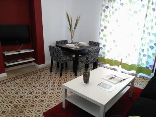 Sala de estar del apartamento en Cáceres con comedor, mesa negra, sillas estampadas, televisor y vistas a la ciudad
