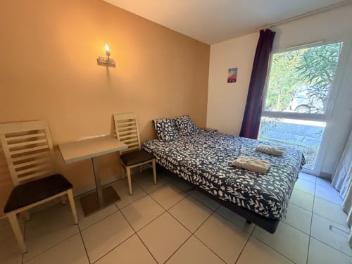 Studio 11 bedroom with patterned bed, desk, chairs, and garden view at Le Clos d'Aix in Southern France
