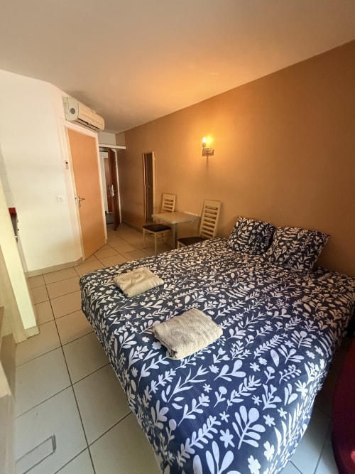 Le Clos d'Aix Studio 11 bedroom with double bed, patterned navy bedding, wooden furniture, and warm ambient lighting in