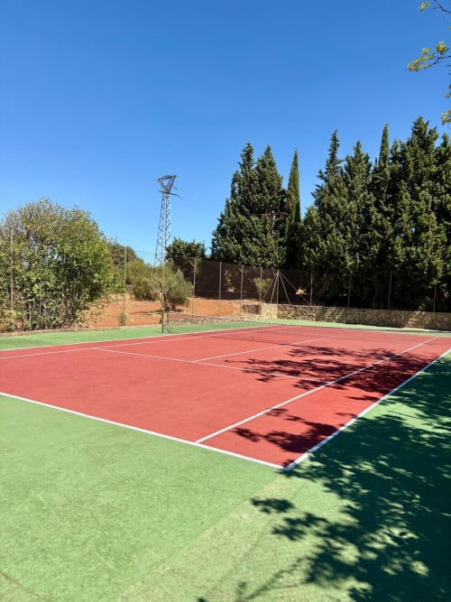 Cancha de tenis en Holiday Dreams Ronda con pistas rojas y verdes, cipreses y vistas a las montañas en Ronda, España
