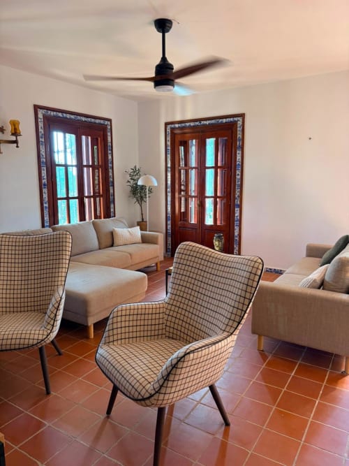 Sala de estar moderna en Holiday Dreams Ronda con sillones estampados, puertas de madera, suelos de terracota y ventilador de techo