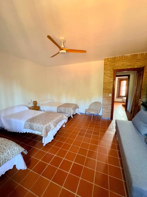 Habitación amplia en Holiday Dreams Ronda con camas individuales, suelos de barro cocido, ventilador de techo y detalles de ladrillo