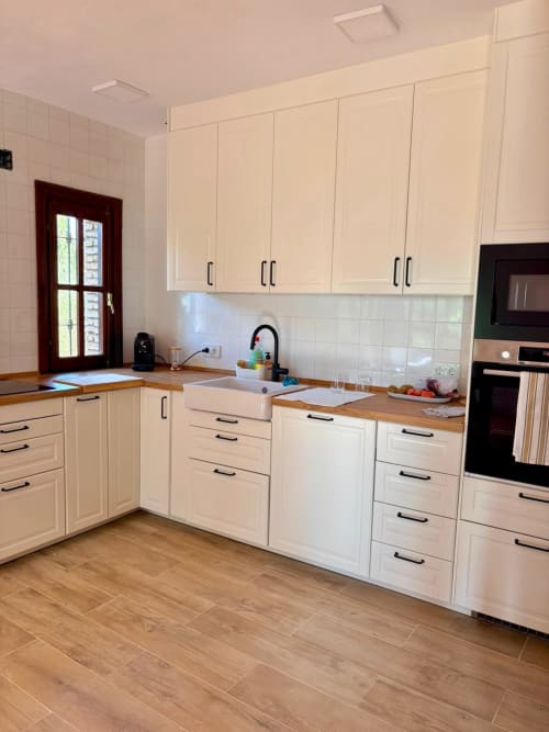 Cocina moderna con gabinetes color crema, encimeras de madera, salpicadero de azulejos blancos y electrodomésticos de acero inoxidable en Holiday Dreams