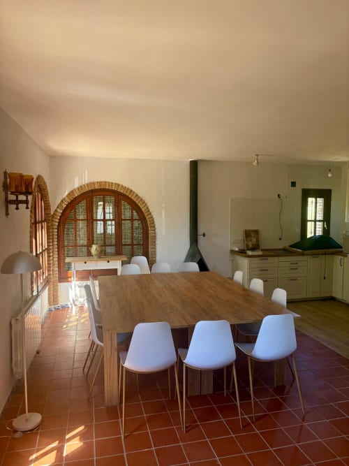 Amplio comedor con mesa de madera, sillas blancas, ventana arqueada de ladrillo y cocina moderna en Heredad La Encarnación