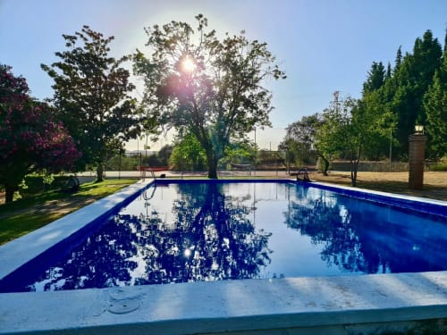 Piscina del resort con agua azul que refleja los árboles y el sol en Holiday Dreams Ronda en España