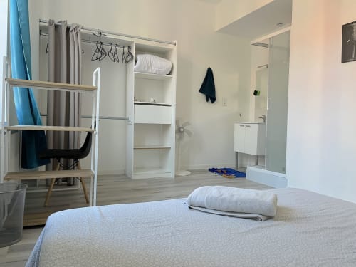 Chambre d'hôtel moderne à la Conciergerie-lilloise avec lit, penderie, étagères, bureau et salle de bain privée avec vue sur la ville