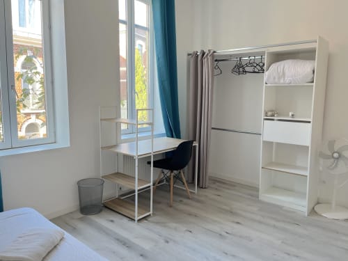 Chambre d'hôtel moderne à la Conciergerie-lilloise avec bureau, armoire, lit et vue sur la ville