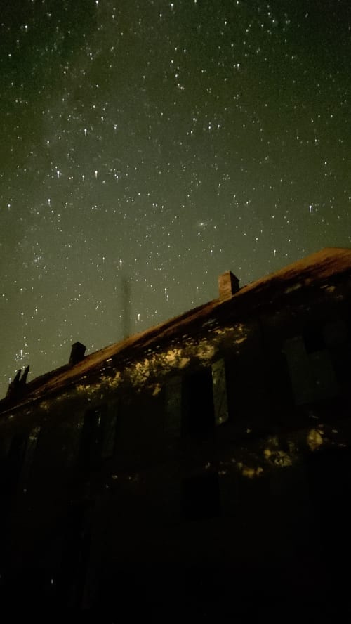 Starry night sky above rustic roofline at Château de Vaux Morvan, Étang sur Arroux