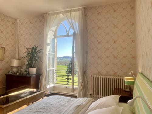 Bedroom at Château de Vaux Morvan with arched windows overlooking countryside near Étang sur Arroux, France