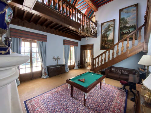 Elegante sala de billar en el Domaine de Bize Mirepoix con mesa de juego, escalera de madera y mobiliario de época en Ariège