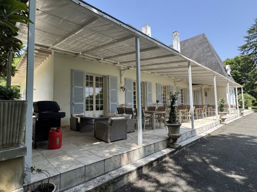 Elegante patio cubierto con zona de comedor en Domaine de Bize Mirepoix, un hotel con mansión francesa en Ariège con columnas blancas