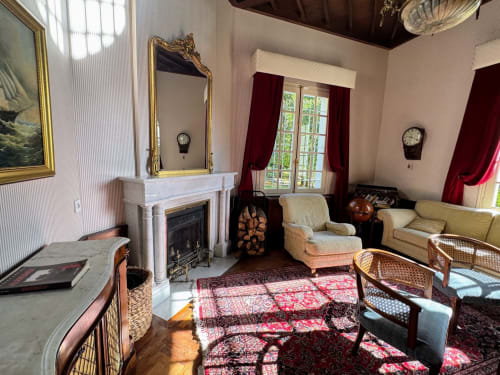 Elegante sala de estar con chimenea, espejo dorado y muebles de época en el Domaine de Bize Mirepoix en Ariège
