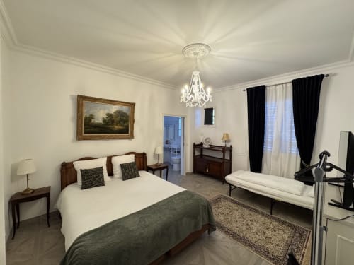 Elegante habitación en Domaine de Bize Mirepoix con cama de madera, lámpara de araña de cristal y servicios modernos en Ariège