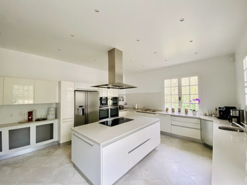 Cocina blanca moderna con isla y electrodomésticos de acero inoxidable en Domaine de Bize en Mirepoix, Francia