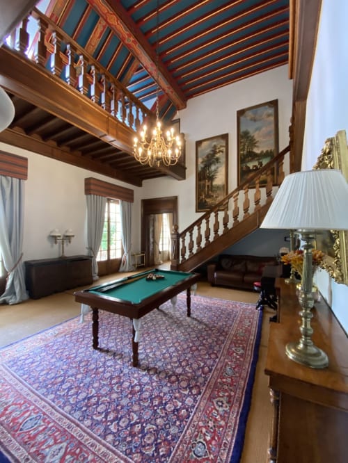 Elegantes Spielzimmer in Domaine de Bize mit Billardtisch, Holzbalken, Kronleuchter und prachtvoller Treppe
