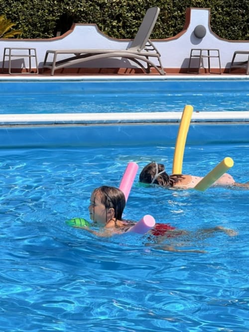 Bambini che nuotano con i tappetini in piscina presso l'hotel Casa Pineta a Marina di Campo