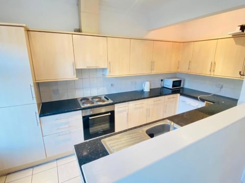 Modern kitchen with light wood cabinets, black countertops, and stainless steel appliances at Catherines House Kings Cross,