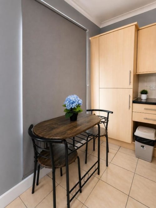 Cozy kitchenette at Catherines House Kings Cross with dining table, blue hydrangea, and wooden cabinetry