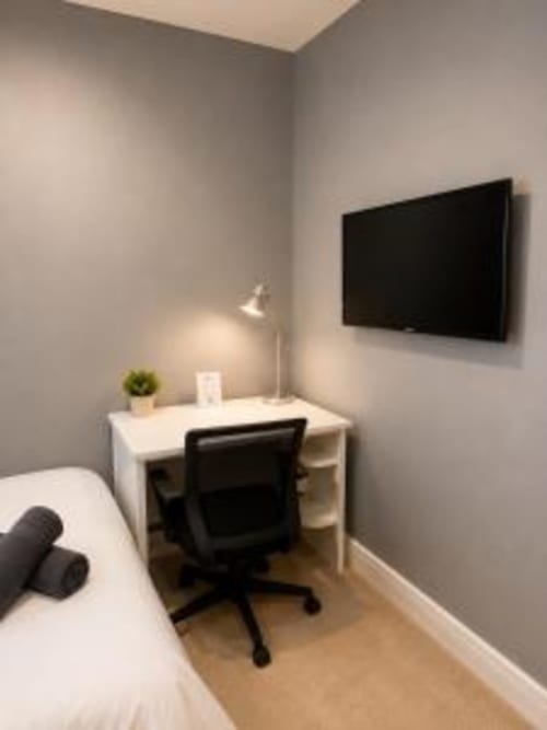 Modern bedroom at Catherines House Kings Cross with desk, TV, bed, and lamp in London