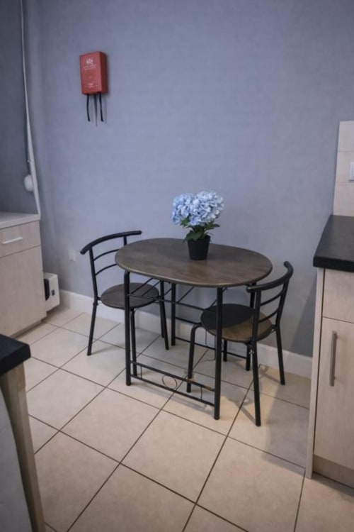 Cozy dining area in Room 1 at Catherines House Kings Cross, London with small table, black chairs and blue flowers