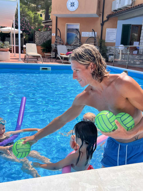 Insegnante che mostra il water volley ai bambini nella piscina di Casa Pineta, Marina di Campo