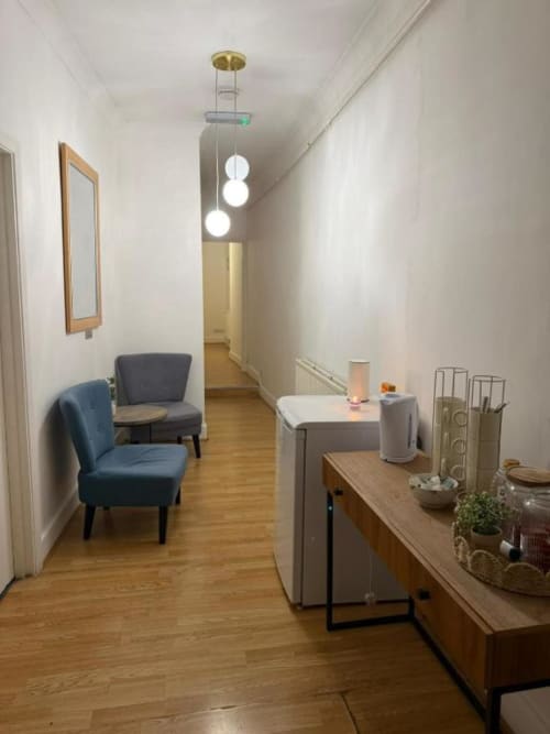 Modern corridor at Catherines House Kings Cross with blue chairs, pendant lights, wooden desk, and contemporary decor