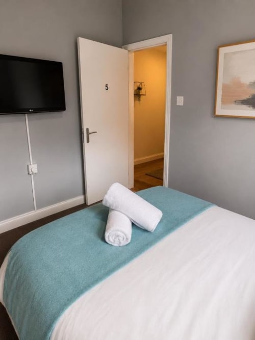 Room 5 at Catherines House Kings Cross, London - bed with white towels, TV, and ensuite bathroom door