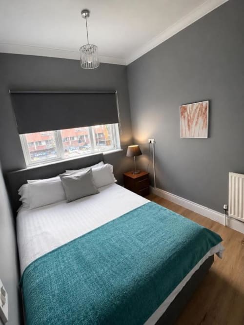 Modern bedroom at Catherines House Kings Cross with grey walls, teal blanket, and city views