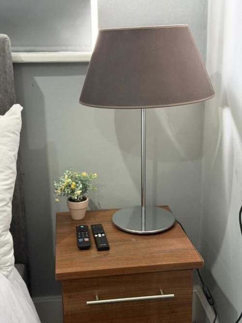 Bedside lamp with brown shade on wooden nightstand in Catherines House Kings Cross London room