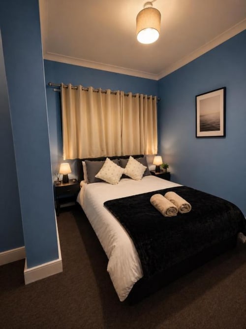Modern bedroom at Catherines House Kings Cross with blue walls, queen bed, gold curtains, and contemporary lighting