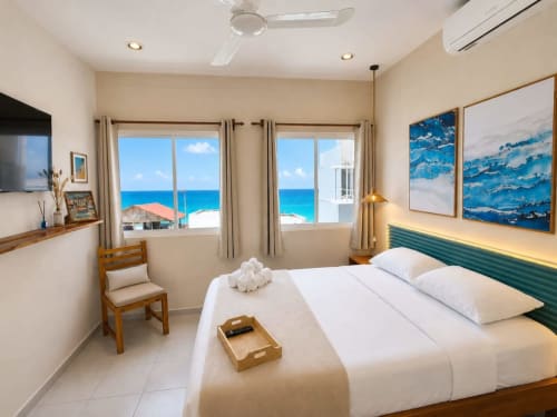 Habitación moderna frente al mar en Hotel Holbox Centro con vistas al océano, cama con cabecera verde y mobiliario contemporáneo.