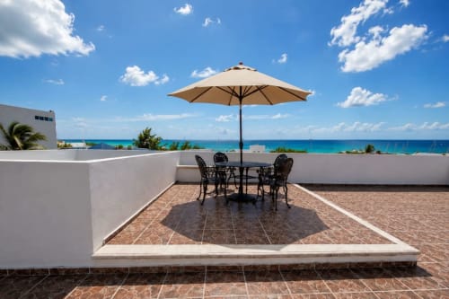 Terraza en la azotea del Hotel Holbox Centro con sombrilla, asientos y vistas turquesas del Caribe