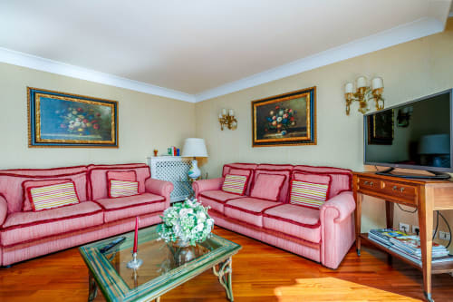 Élégant séjour avec canapés roses, tableaux floraux encadrés et vue sur la mer à Riviera Home, Roquebrune-Cap-Martin