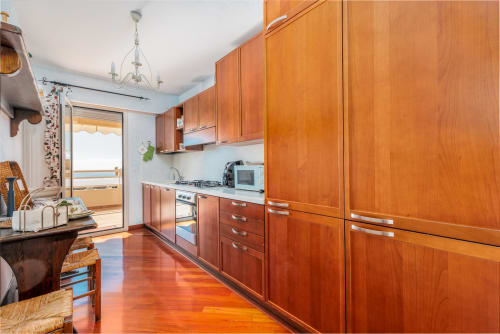 Cuisine moderne avec meubles en bois, électroménagers inox et balcon avec vue mer à Riviera Home, Roquebrune-Cap Martin