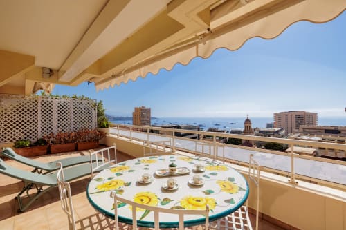 Terrasse ensoleillée de Riviera Home Roquebrune-Cap Martin avec vue mer, table à manger, transat et plantes en pot
