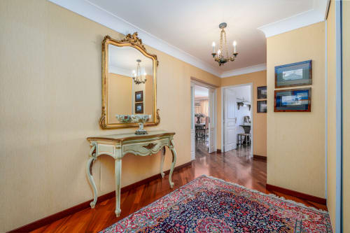 Élégant hall d'entrée de la Riviera Home à Roquebrune-Cap Martin, avec miroir ouvragé, console, lustre et tapis à motifs.