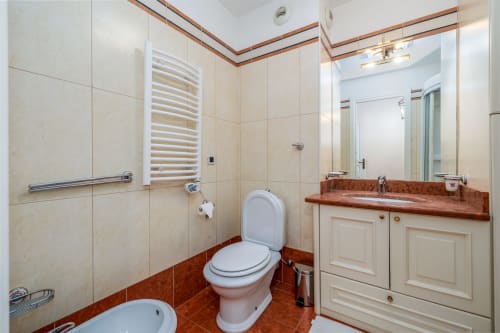 Salle de bains moderne à Riviera Home, Roquebrune-Cap Martin, avec carrelage crème, accents en marbre rouge, toilettes blanches et lavabo