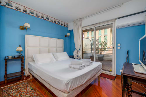 Chambre d'un bleu éclatant à la Riviera Home à Roquebrune-Cap Martin avec lit blanc, balcon vue mer et parquet.
