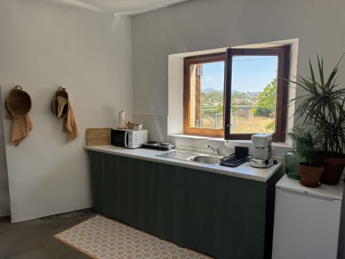 Moderna cuina americana de l'apartament Séncies Can Girona a Sitges, amb vistes al jardí a través de finestres obertes