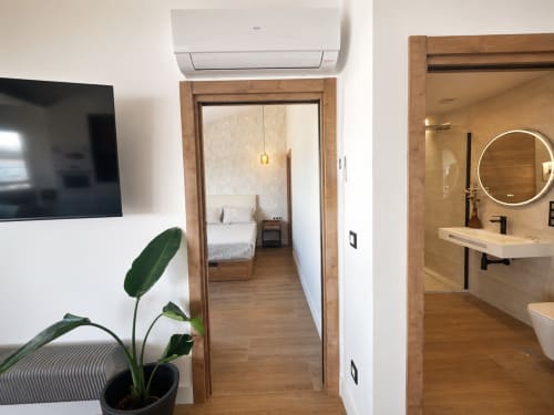 Moderno pasillo de apartamento del hotel Holibai en Baiona con suelos de madera, acceso a dormitorio y baño, TV y aire acondicionado