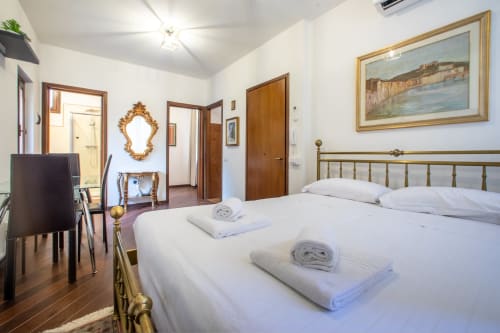 Camera luminosa a Ilary's House a Verona con letto matrimoniale, testiera in ottone e quadri con veduta della città