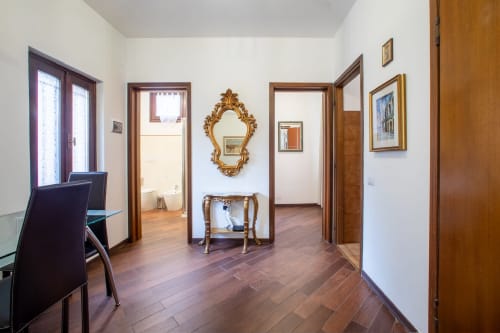 Elegante corridoio nell'appartamento Ilary's House a Verona, con pavimentazione in legno, specchio ornato e múltipli ingressi